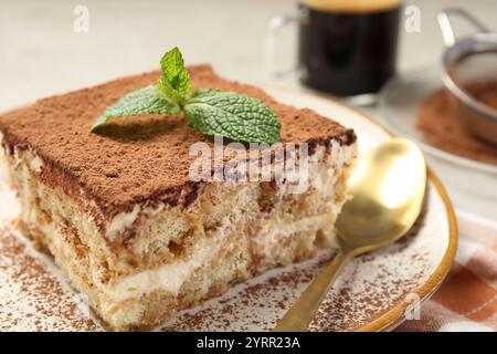 Piece of tasty tiramisu with fresh mint on table, closeup Stock Photo