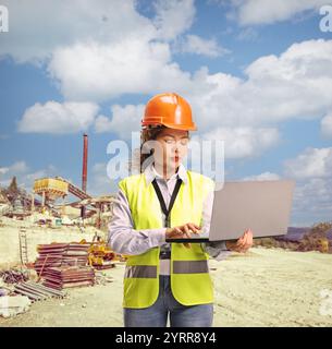 Female asian engineer using a laptop computer at a construction site Stock Photo