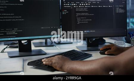 Programmer in server farm workspace protecting data threatened by hacking attacks on computers. IT professional writing code, safeguarding data center from unauthorized access, camera B close up Stock Photo