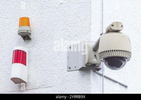 Surveillance camera with warning light on house wall Stock Photo