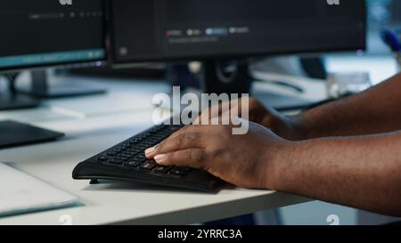 Programmer in server farm workspace protecting data threatened by hacking attacks on computers. IT professional writing code, safeguarding data center from unauthorized access, camera A close up Stock Photo