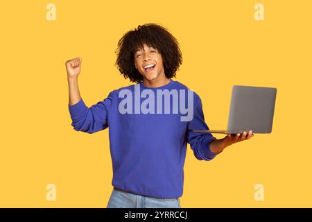 Joyful Brazilian man celebrates success while working on a laptop Stock Photo