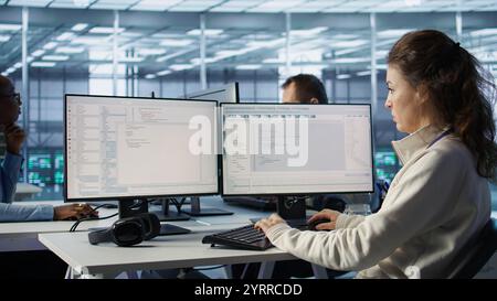 Computer scientist working in diverse computer network security data center workplace, ensuring optimal performance. Software developer monitoring energy consumption across server racks Stock Photo