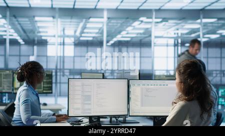 Admin arriving in server hub, sitting at computer desk, checking recovery plan, monitoring data center energy consumption across components, making sure sensors are functioning optimally, camera A Stock Photo