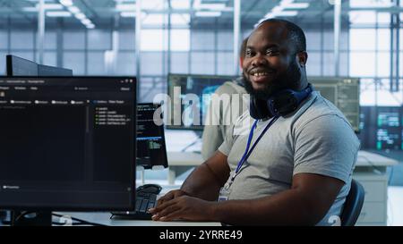 Portrait of joyful technician working in high tech workplace providing computing resources for different workloads. Radiant IT specialist tasked with monitoring data center mainframes, camera A Stock Photo