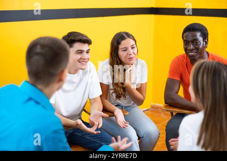 Friendly adult students chatting cheerfully while sitting in classroom Stock Photo