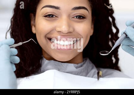 Portrait Of Smiling African American Lady Getting Teeth Treatment At Dental Clinic Stock Photo