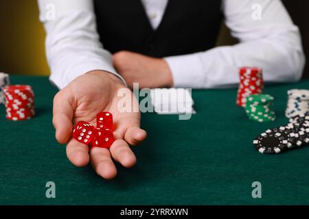 Professional croupier with dice at gambling table, closeup Stock Photo