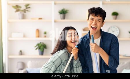 Positive chinese lovers having fun while cleaning house Stock Photo