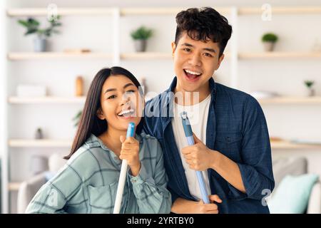Closeup of positive asian lovers having fun while cleaning apartment Stock Photo