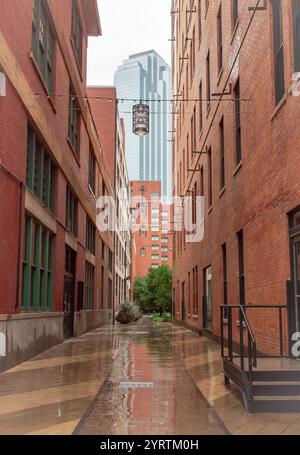 Red brick building alleyway leading to a skyscraper building. Photo taken in downtown Dallas Texas on a rainy day Stock Photo