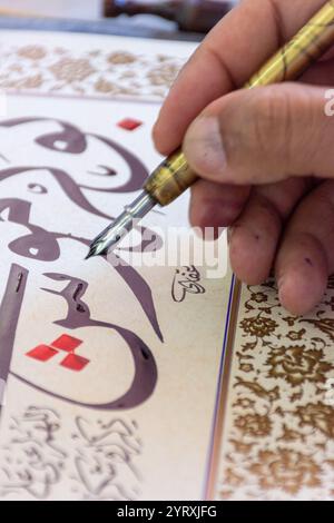 A calligrapher writing a name using a reed pen and ink at the Algiers International Book Fair (SILA), Algeria. Stock Photo