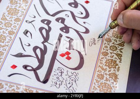 A calligrapher writing a name using a reed pen and ink at the Algiers International Book Fair (SILA), Algeria. Stock Photo