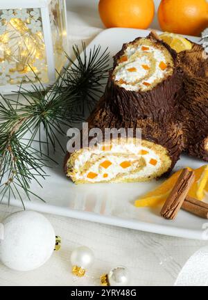 Buche de Noel. Traditional Christmas dessert. Christmas yule log cake with orange cream and chocolate. Christmas decorations. Holiday season. Stock Photo