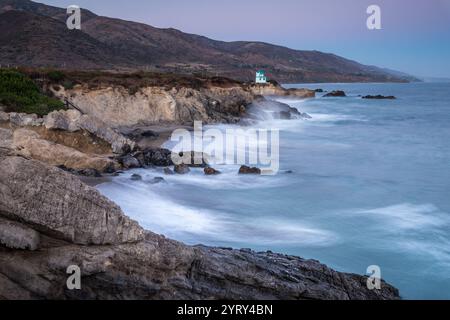 Waves crash against the rocky coastline of Leo Carrillo State Beach at dusk, capturing the serene beauty of Malibu's coastal landscape. Stock Photo