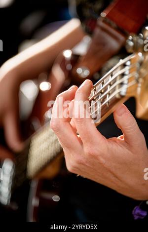 Close-up of a musician’s hand plucking the strings of a bass guitar, emphasizing musical performance, technique, and craftsmanship. Stock Photo