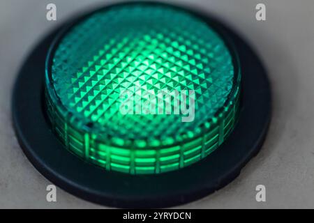 Close-up view of a circular green indicator light emitting a soft, diffused glow, creating a vibrant and reassuring signal Stock Photo