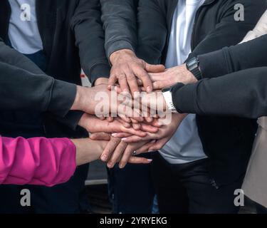 A symbolic image of hands stacked on top of each other, symbolizing teamwork, unity, and collaboration. The close-up composition highlights the Stock Photo