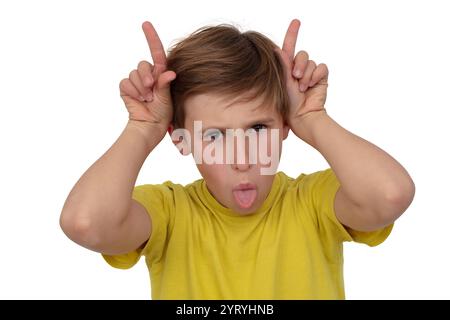 Portrait of a funny boy, he grimaces, shows his tongue and makes horns with his fingers. Stock Photo