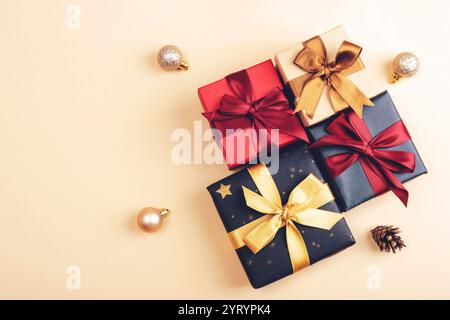 Multiple wrapped gift boxes with golden and red ribbons on a light background, surrounded by baubles and pine cones for a festive Christmas setup. Top Stock Photo