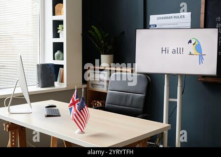 Teachers working desk equipped with computer and digital display in modern classroom of English language school, copy space Stock Photo