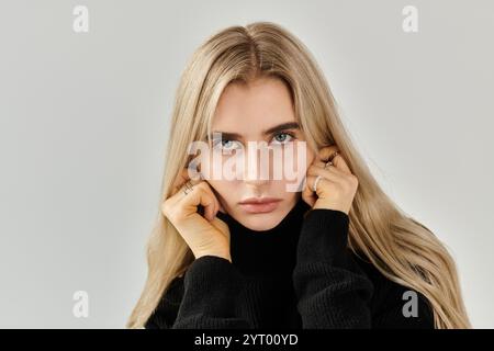 A beautiful young woman with flowing blonde hair poses elegantly, highlighting her fashion sense. Stock Photo