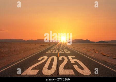 New year 2025 or straight forward concept. Text 2025 written on the road in the middle of asphalt road at sunset. Concept of planning, goal, challenge Stock Photo