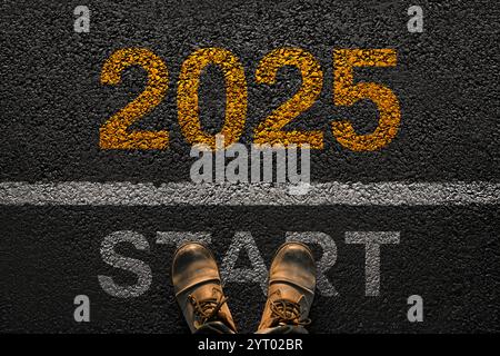 Man walks on asphalt and crosses the line by 2025. New year 2025, creative. Men's legs with leather shoes go to 2025. Start and beginning of 2025, con Stock Photo