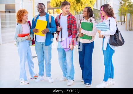 Diverse group of students smiling and walking together outdoors with notebooks Stock Photo