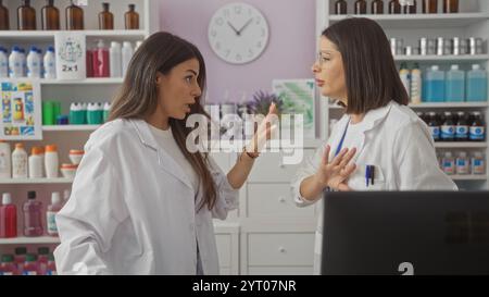 Two hispanic women pharmacists discussing in a pharmacy store interior. Stock Photo