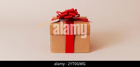 a brown gift box, tied with red ribbon and topped with a red ribbon bow, with a paper tag attached to it, on a beige surface, in a panoramic format to Stock Photo