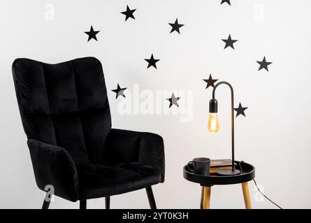 Black color star shape wall stickers on home living room wall, minimalist home decor concept. Black arm chair and coffee table with electric lamp. Stock Photo