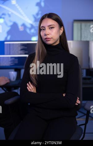 Portrait of a confident female Cybersecurity Analyst or Manager in large Cyber Security Operations Center SOC handling Threats Stock Photo