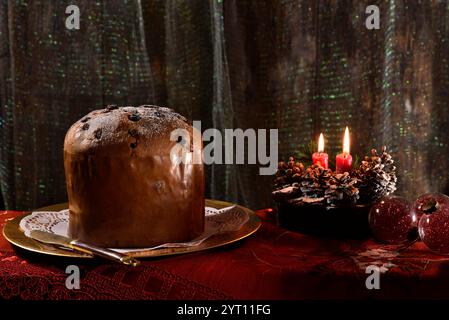 Whole CWhole Christmas panettone on a golden tray, with lighted candles and decorations nearby. typical Italian dessert Stock Photo