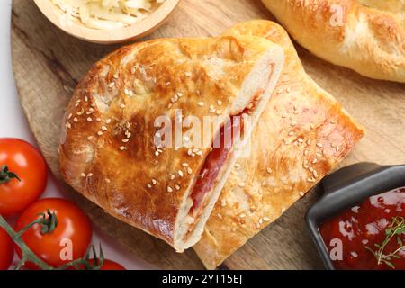 Pieces of fresh calzone pizza served on white wooden table, top view Stock Photo