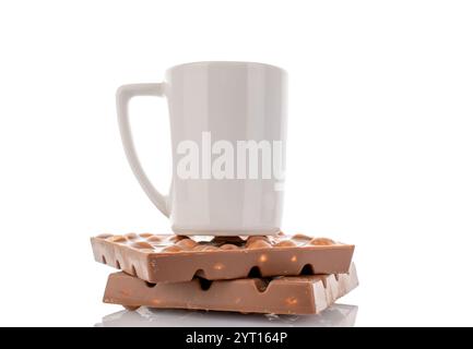 Two bars of dark chocolate with hazelnuts in a ceramic dish, close-up, isolated on a white background. Stock Photo