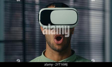 Surprised african american man take off VR glasses in 3D metaverse world play online male gamer enjoying video game using virtual reality headset Stock Photo