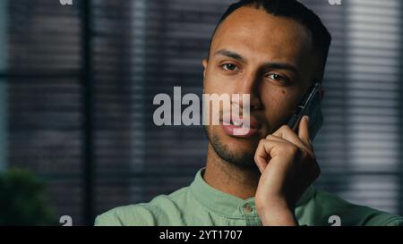 Serious worried excited latin american man talking mobile phone sad frustrated confused young businessman hear bad news feel stress experience have Stock Photo