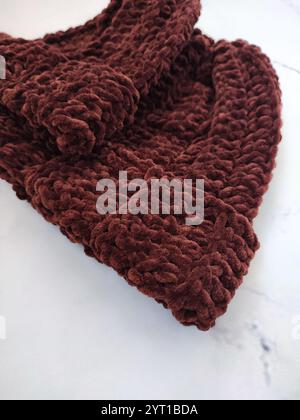 Knitted hat, dark brown chocolate beanie hats on white marble background top view flat lay, velor, velvet, crochet, pair, set, autumn winter headwear Stock Photo