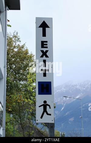 Directional Exit Sign with Arrow and Running Icon Against Mountainous Backdrop in Bergisel, Innsbruck, Austria Stock Photo
