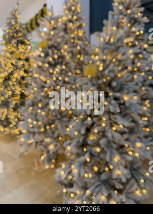 This horizontal photo, taken during the day, features a dreamy view of snowy Christmas trees adorned with golden fairy lights. The soft-focus effect a Stock Photo