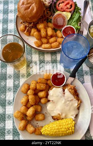Hearty American Meal with Pulled Pork Sandwich, Fried Chicken, Tater Tots, and Corn on the Cob Stock Photo