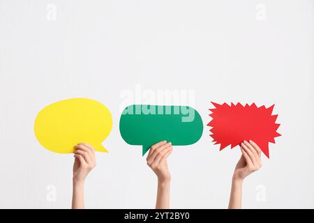 Female hands with colorful speech bubbles on white background Stock Photo