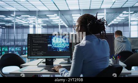 Engineer typing on computer in server hub, monitoring data center energy consumption using AI software. Technician inspecting rackmounts in server room using artificial intelligence tech, camera B Stock Photo
