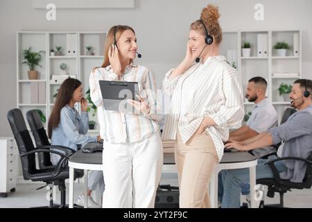 Female technical support agents with headsets and clipboard in office Stock Photo
