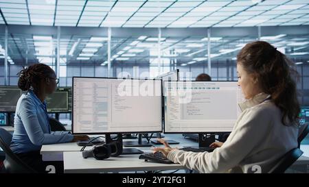 Team of admins doing yearly checkup to prolong data center electronics life span and avoid downtime. Teamworking colleagues in server room monitoring server infrastructure components, camera B Stock Photo