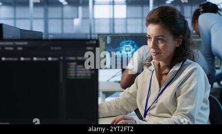 Joyful technician working in high tech workspace providing computing resources for different workloads. Relaxed woman tasked with monitoring data center supercomputers, camera A Stock Photo