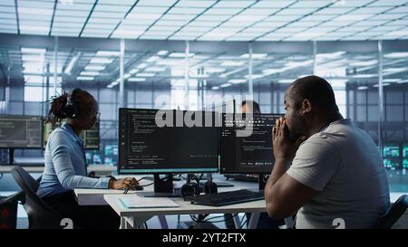 Admin working in computer network security data center suffering from cold, sneezing. Ill african american worker coughing while monitoring server racks, coming up with flu, camera B Stock Photo