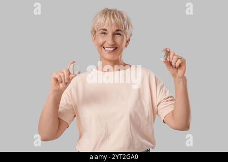 Mature woman with hearing aids on  grey background Stock Photo
