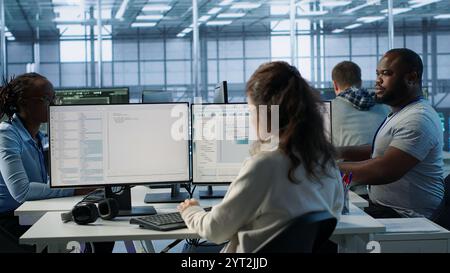 Team of admins doing yearly checkup to prolong data center electronics life span and avoid downtime. Teamworking colleagues in server room monitoring server infrastructure components, camera A Stock Photo